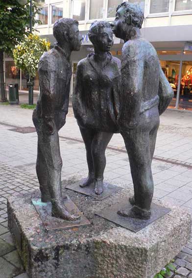 bronseskulptur av to gutter og ei jente i tenårene som prater sammen som står i en sirkel